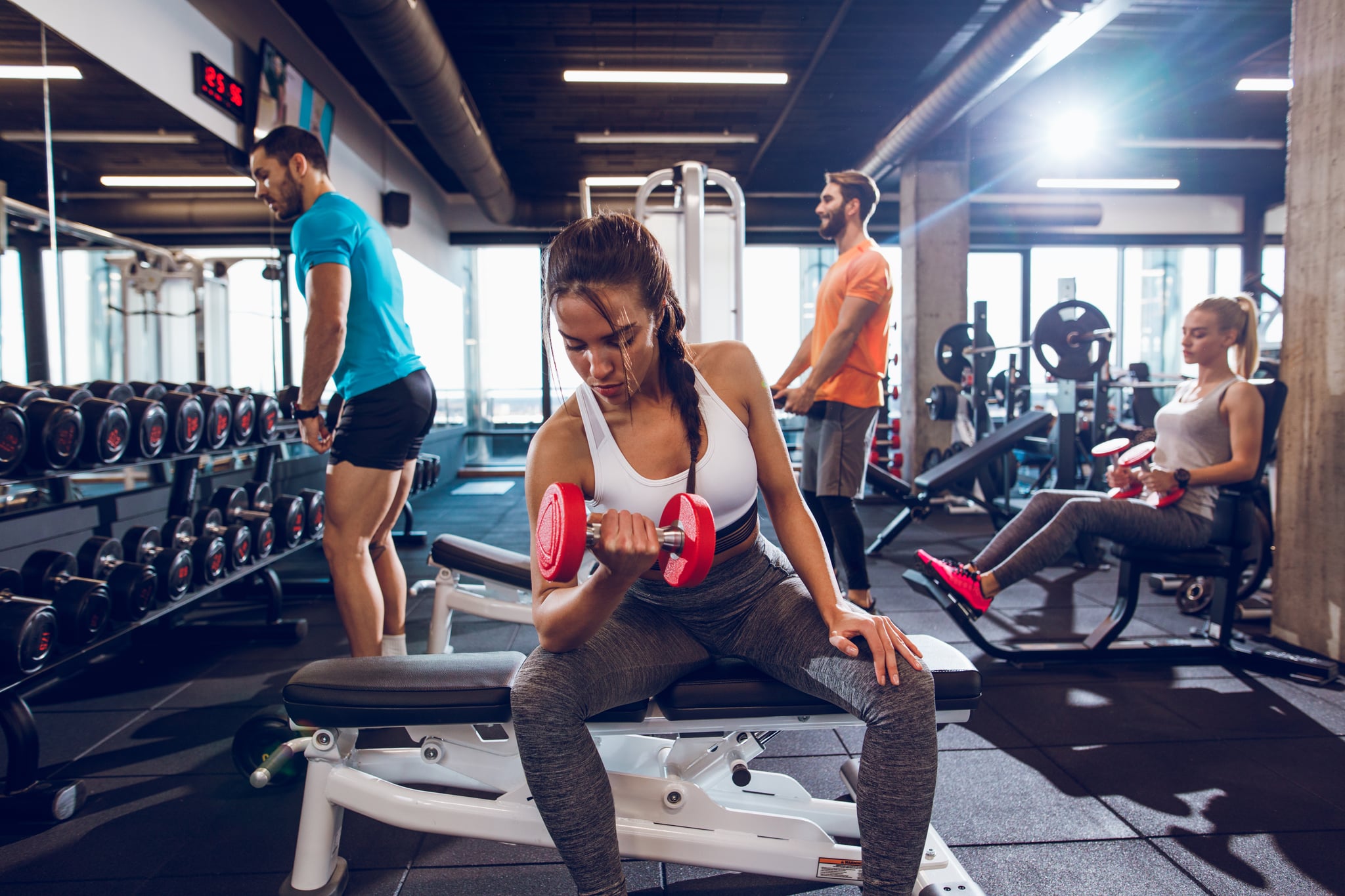 Young woman working out with dumbbells at gym