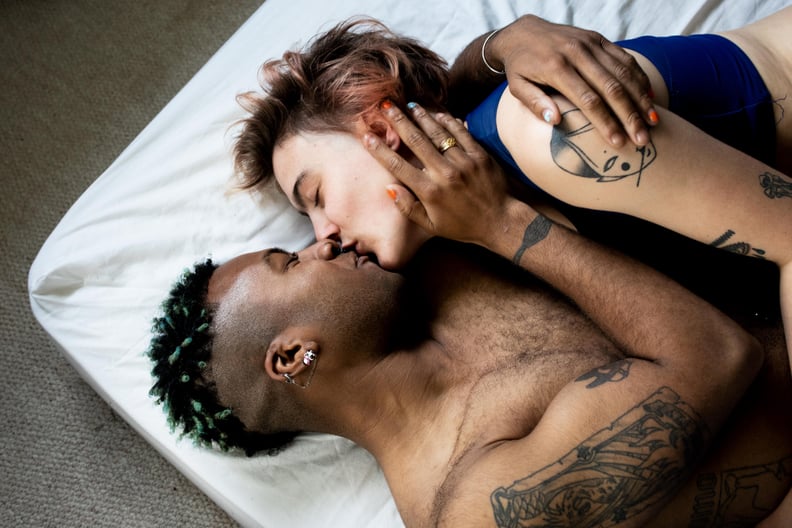 Young Couple In Bed on White Mattress Sharing a Kiss