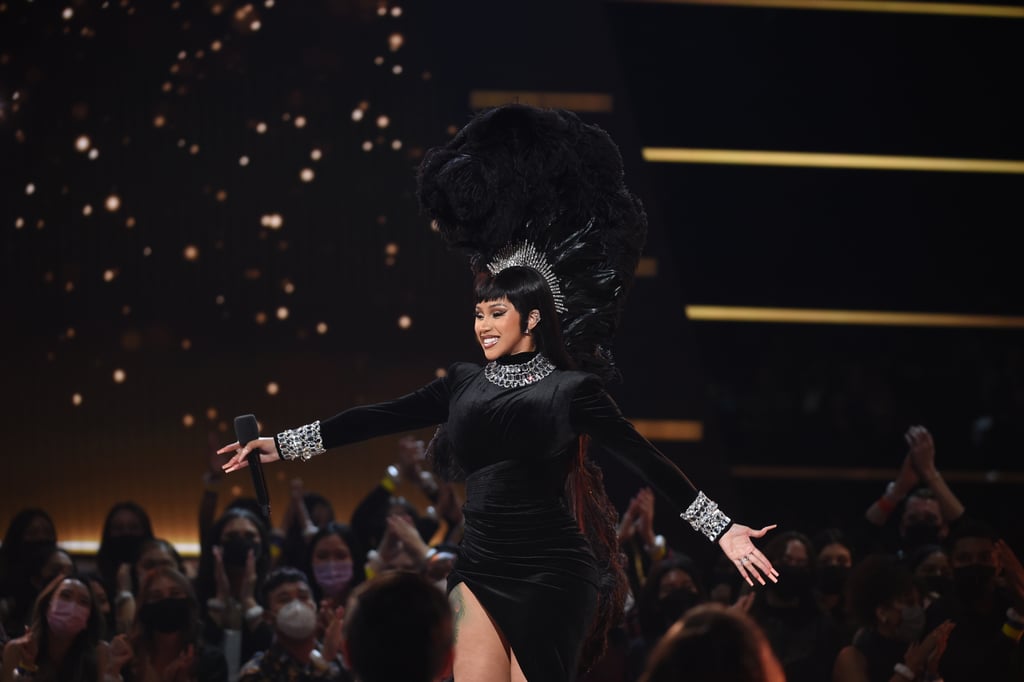 To kick off the show, Cardi B took the stage in a long-sleeve slitted dress and giant feathered headpiece.