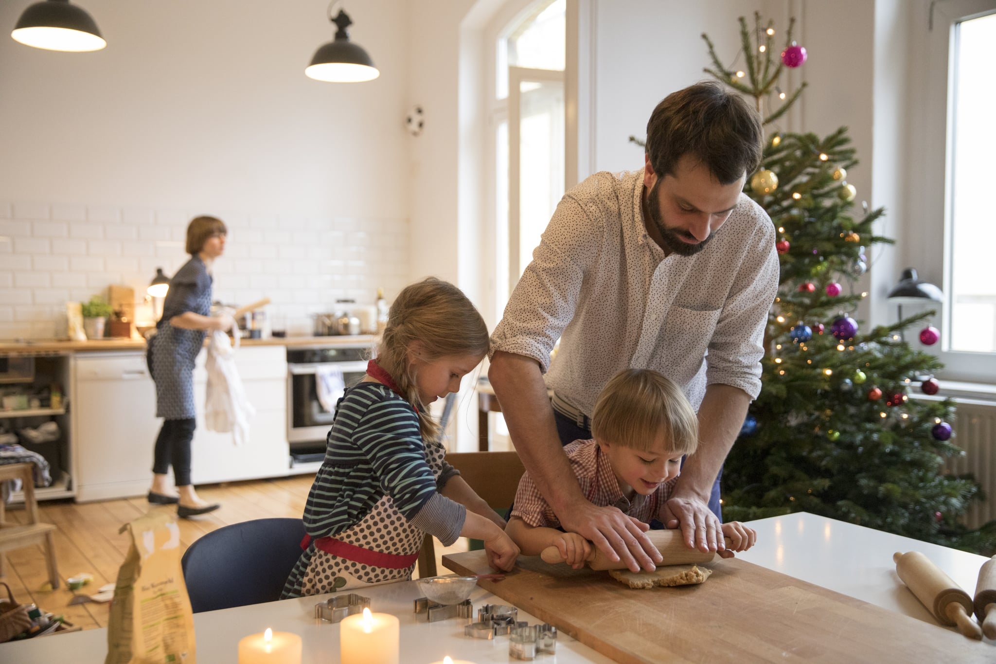 Caucasian father preparing cookies with todller girl and boy at table in living room