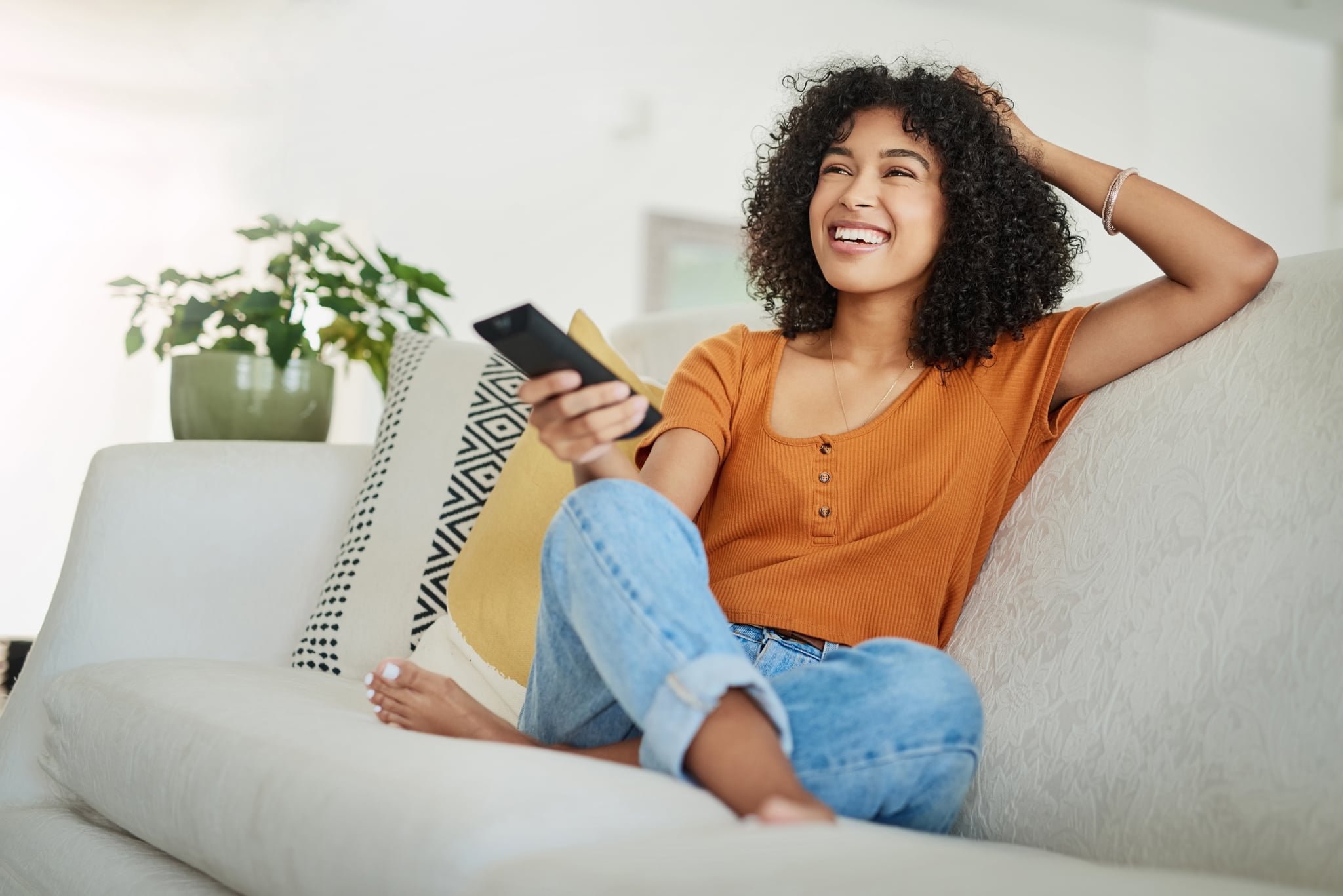 Shot of a young woman relaxing on the sofa and watching tv