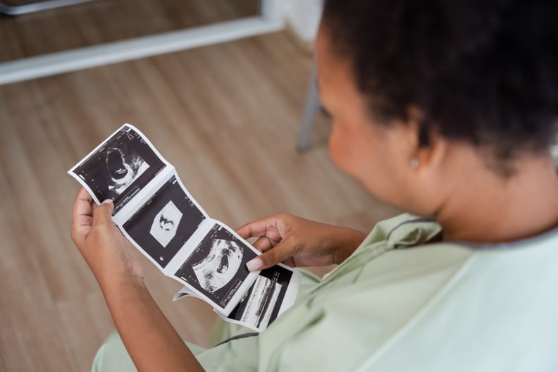Young black mother in a hospital gown looking at ultrasound images in the hospital