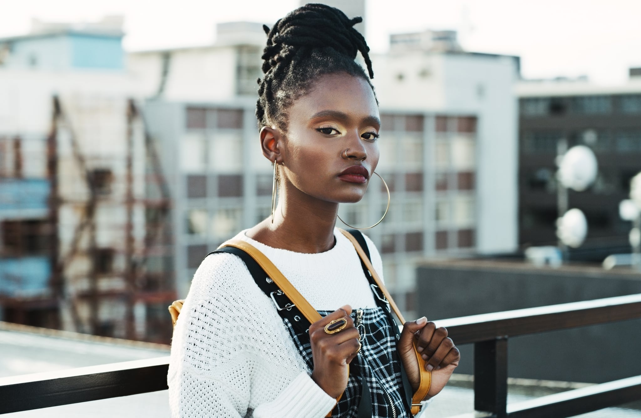 Woman on Top of Building Staring at Camera With Yellow Backpack 