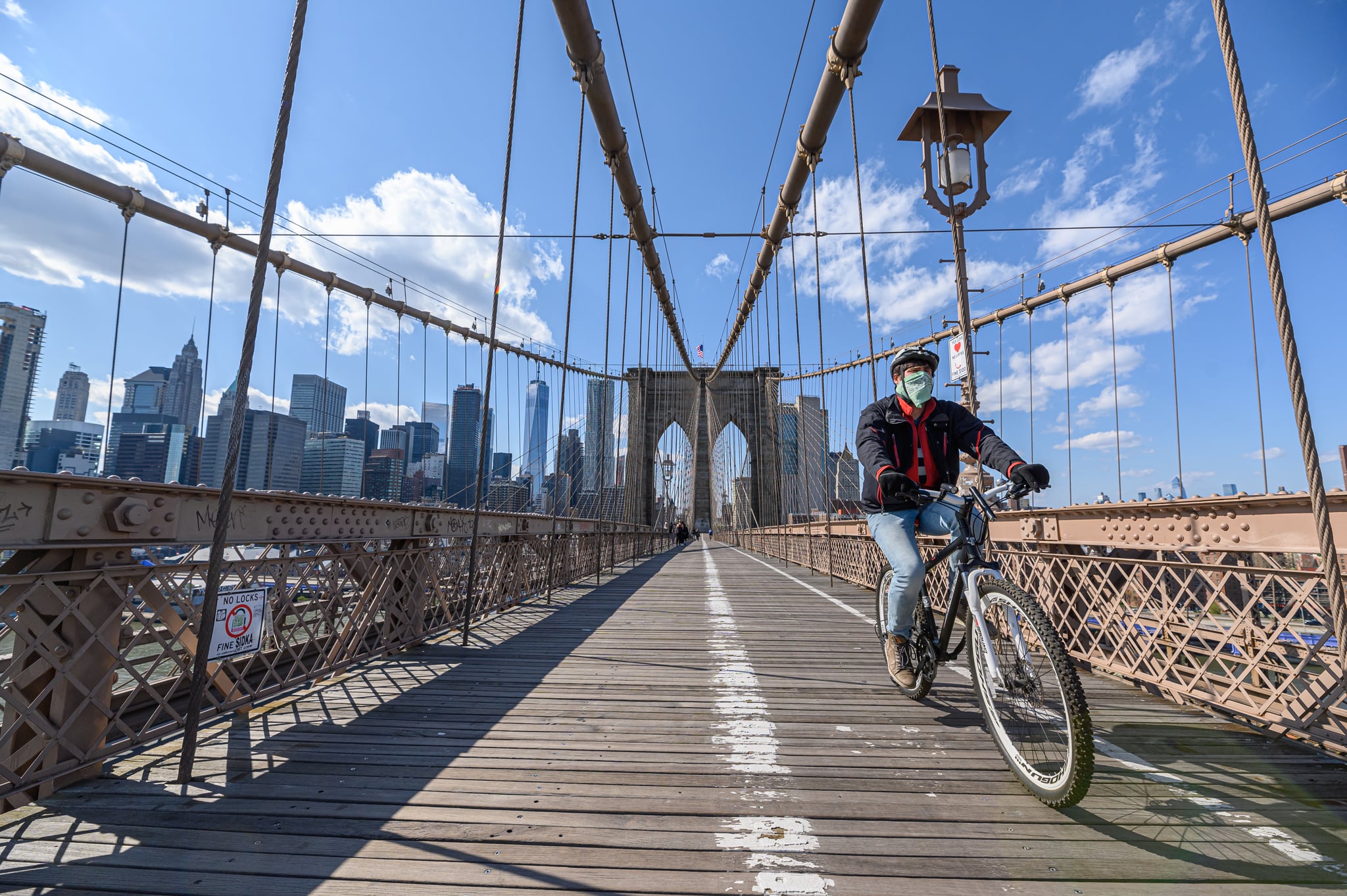 NEW YORK, NY - APRIL 15: A man wearing a protective mask rides a bicycle on the Brooklyn Bridge during the coronavirus pandemic on April 15, 2020 in New York City. COVID-19 has spread to most countries around the world, claiming over 134,000 lives lost with over 2 million infections reported. (Photo by Noam Galai/Getty Images)