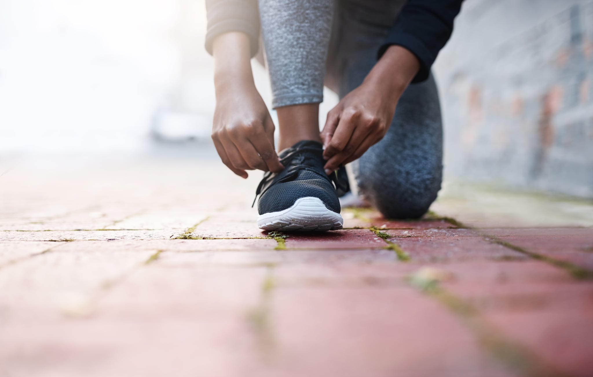 Cropped shot of a woman tying her shoelaces before a workout session