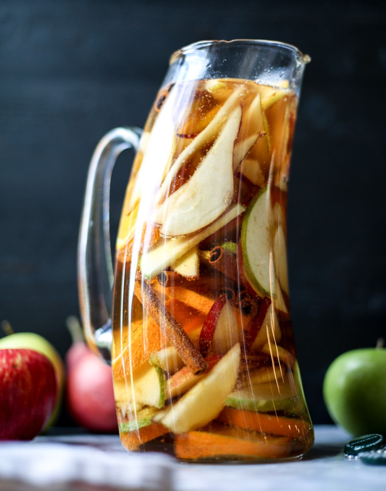 Pitcher of apple cider sangria with sliced apples and cinnamon