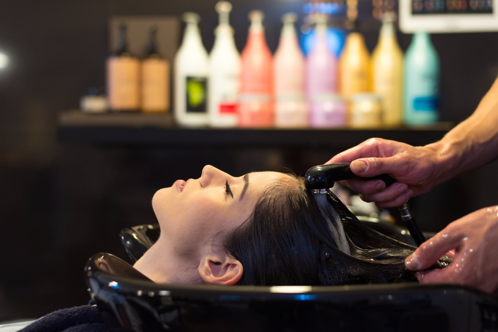Young woman washing hair in the professional hair salon.