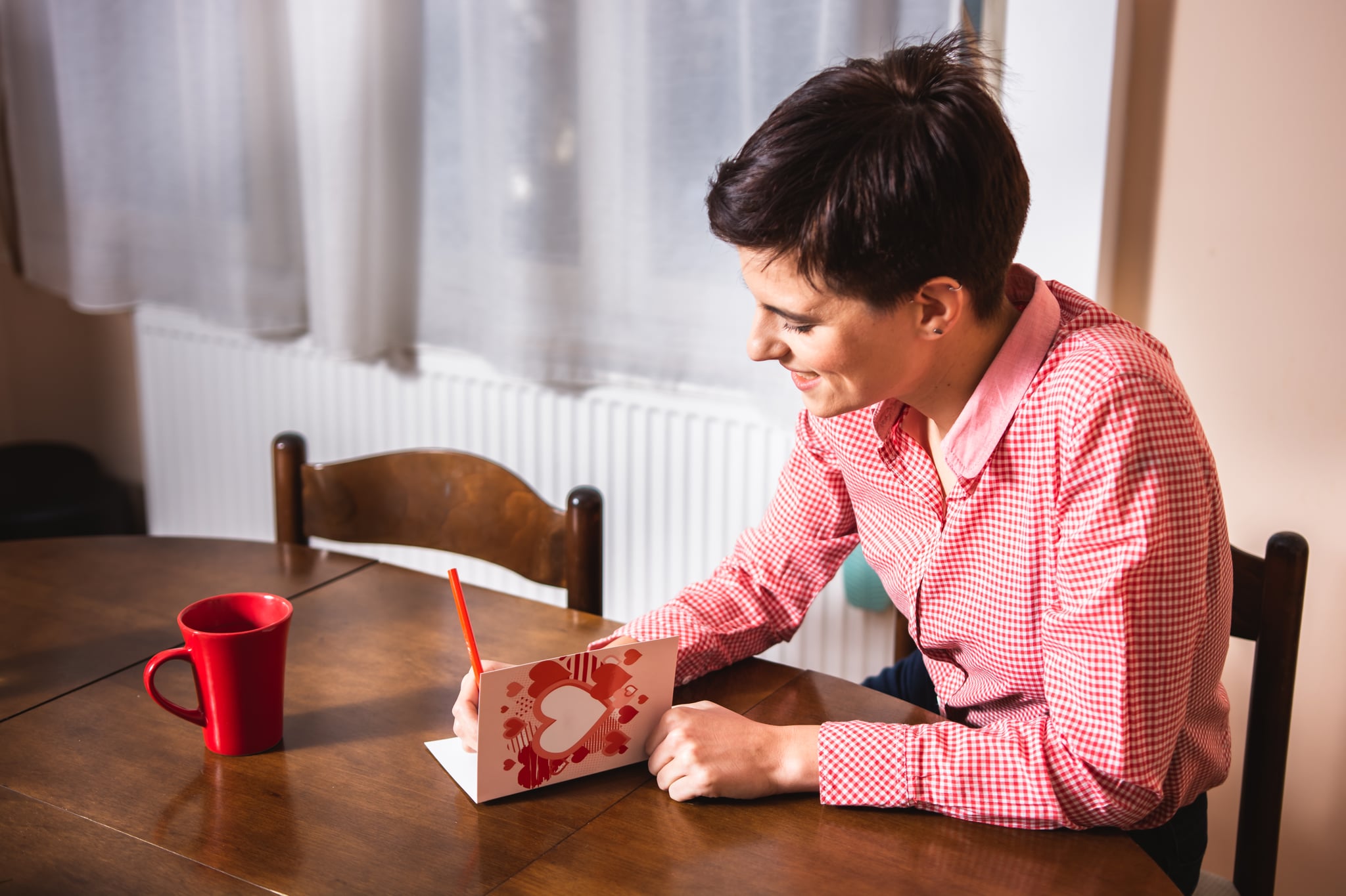 Young woman writing a valentine card indoors.