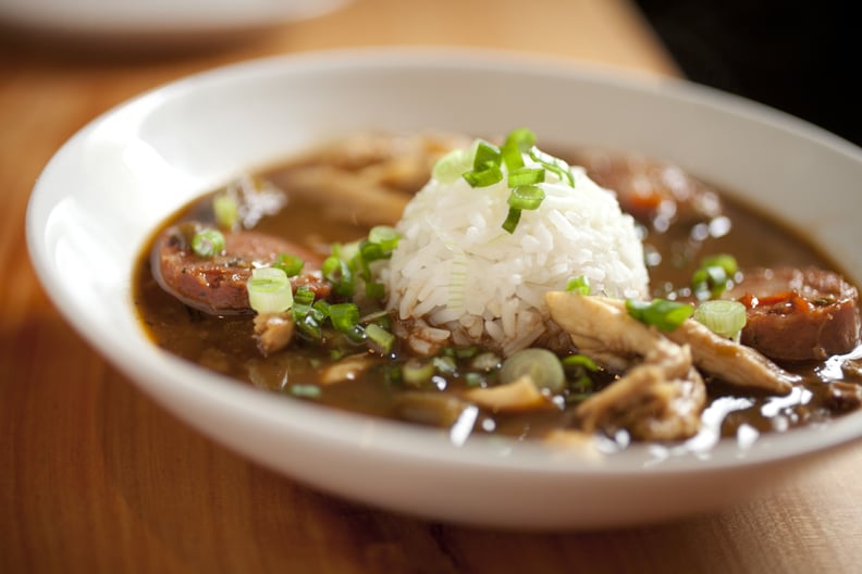 Close up of delicious, hearty chicken gumbo with big chunks of chicken and thick slices of andouille sausage.  finished off with a scoop of rice in the middle.