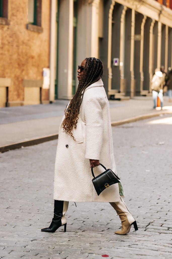 Jessica Andrews in Wandler black and cream boots, Indy black sunglasses, a white coat, and a Balenciaga Hourglass handbag from Vivrelle.