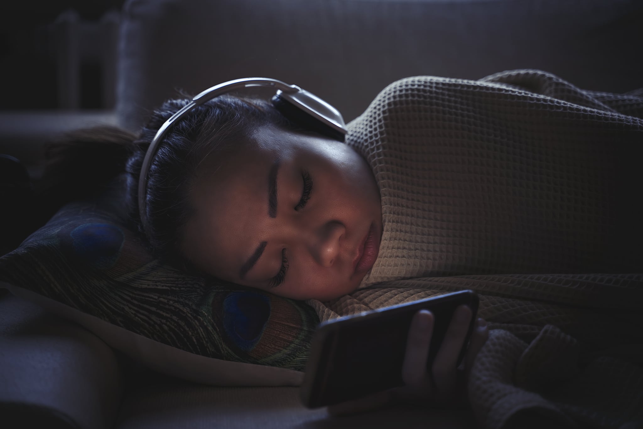 Woman fall a sleep while using mobile phone on couch with headphone