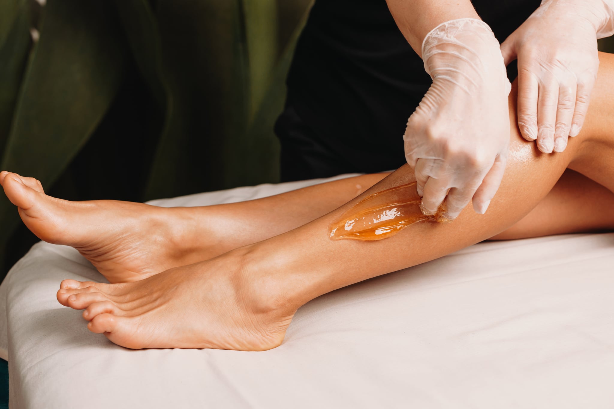 Close up photo of a sugaring procedure done at the salon during a leg skin protection session