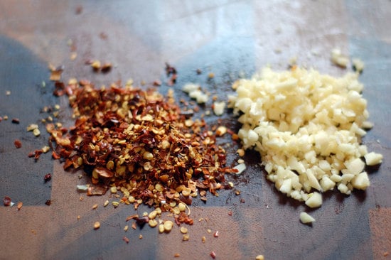 Grab red pepper flakes and chop a few cloves of garlic.