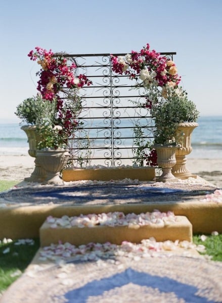 With large potted plants and gorgeous, sprawling flowers, a sculptural piece is transformed into a beautiful backdrop that's perfect for a romantic beach wedding.
Photo by Braedon Photography via Style Me Pretty