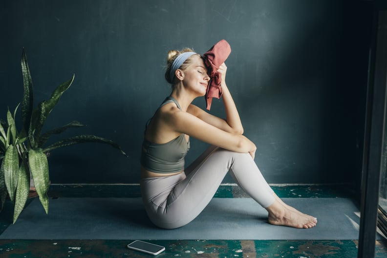 Smiling woman wiping off sweat with a towel after a home workout.