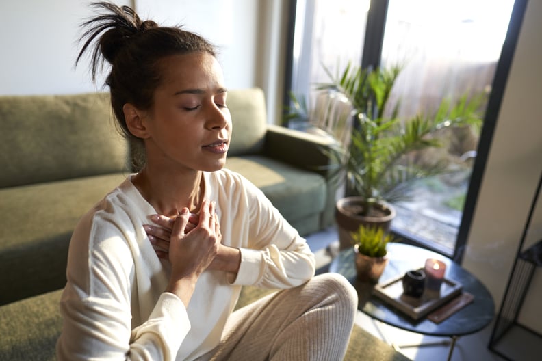 Mixed race woman meditating at home with eyes closed