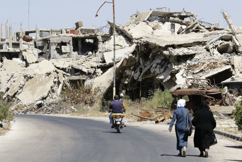 Civilians walk past rubble in the Western Syrian city Homs.