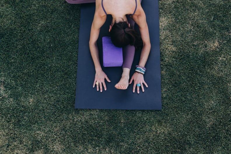 Mexico, Queretaro State, Queretaro City - June 5, 2020: Mexican woman, aged 35-39 years old and of Mexican ethnicity, doing yoga stretching exercises on a mat on a grass surface.