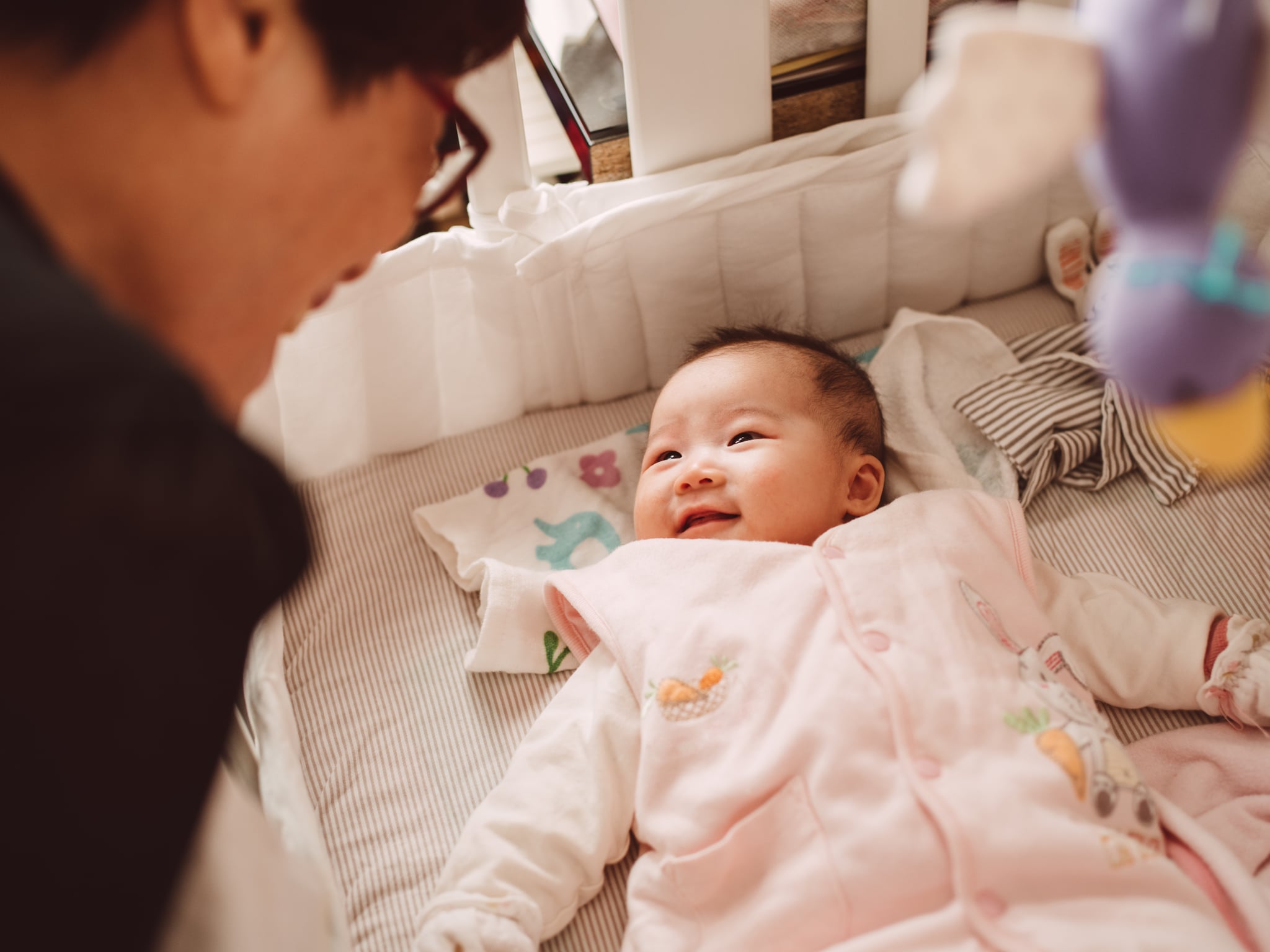 Grandma talking joyfully to the adorable new born baby while the baby lying in the crib