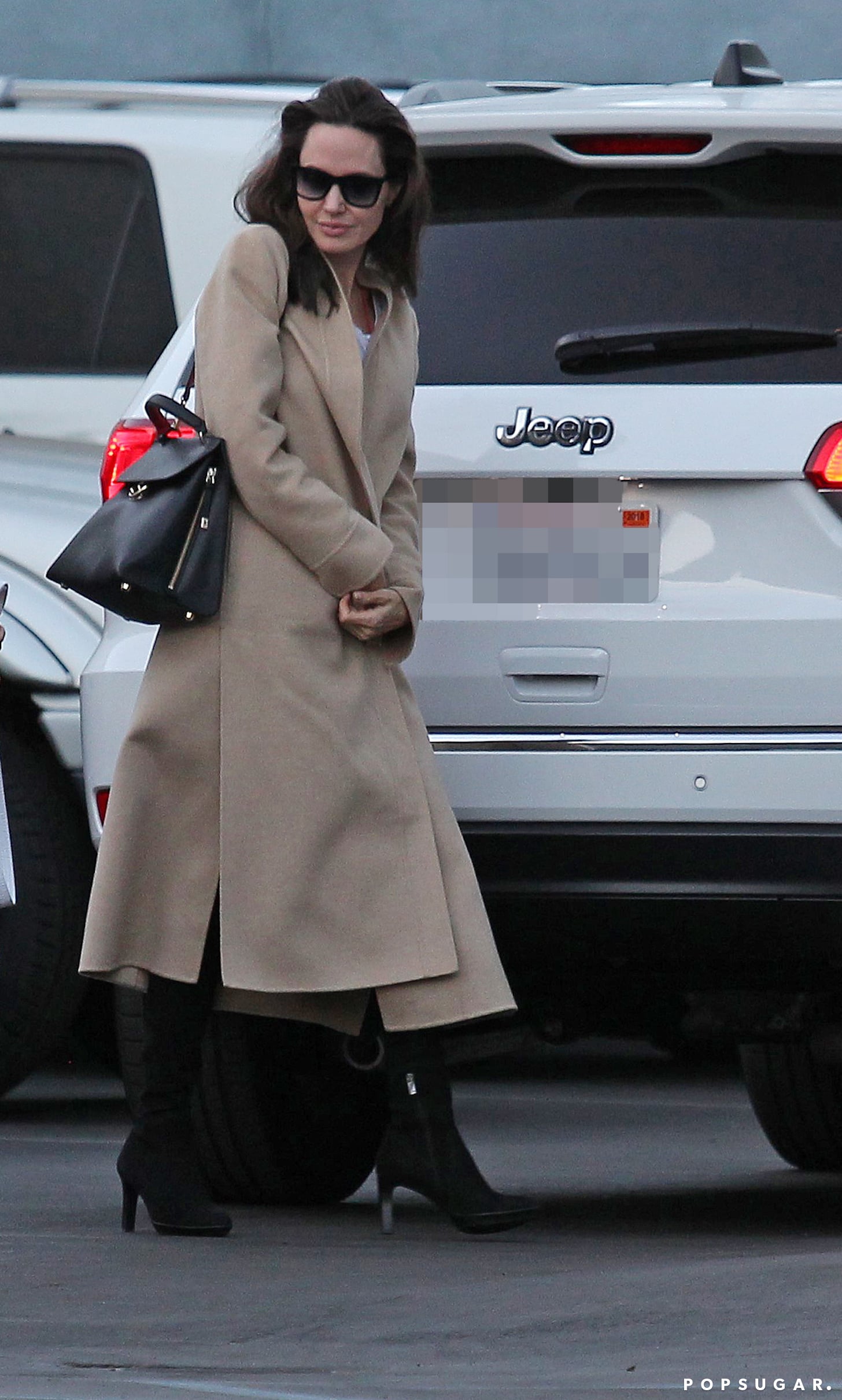 angelina jolie looks classy in a long black coat as she goes