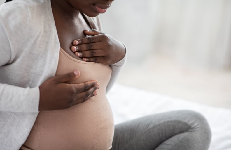 Black pregnant woman suffering painful feelings in breast.