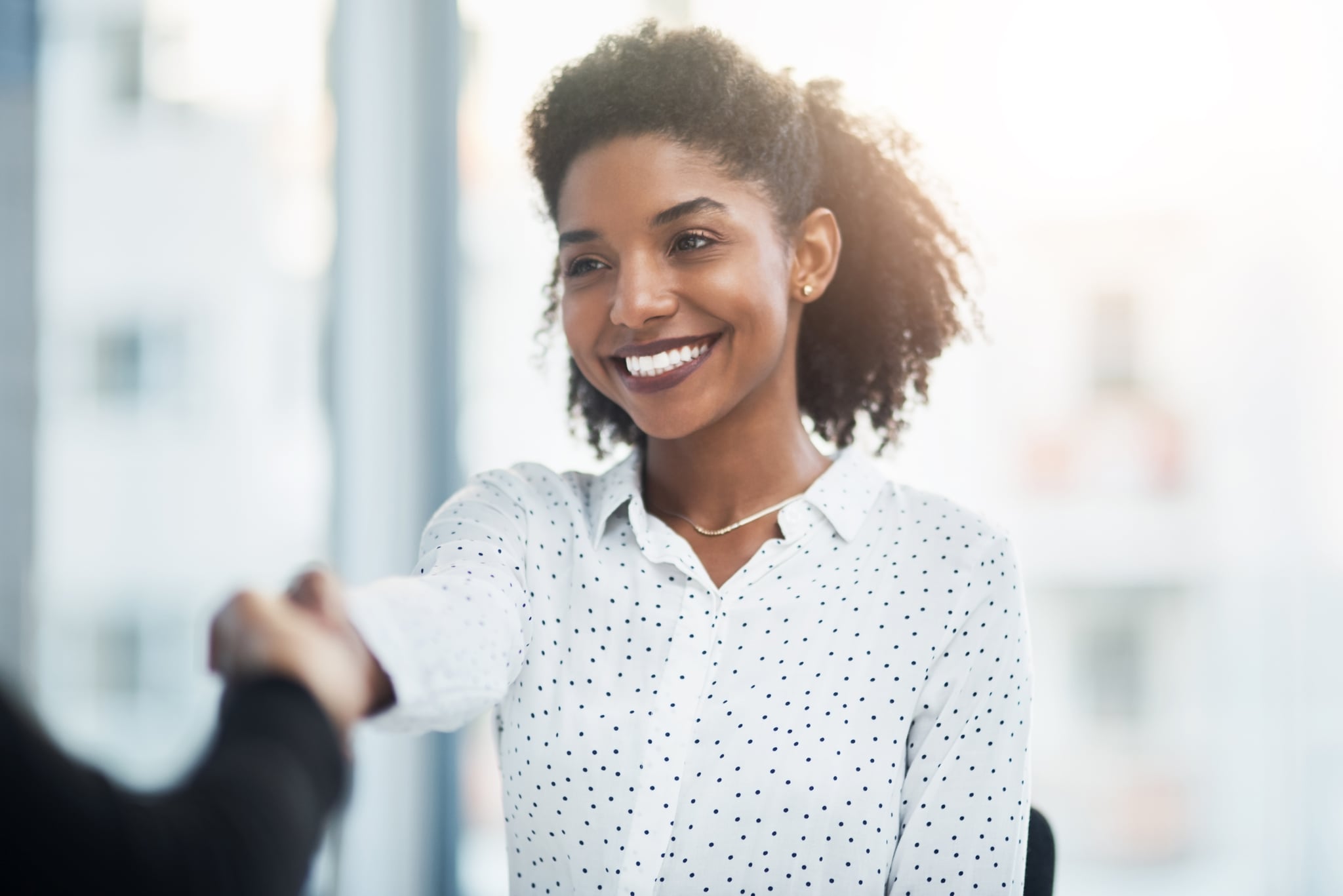 Shot of a young businesswoman shaking hands with a colleague in a modern office