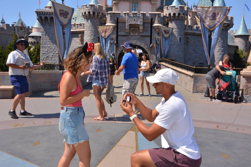 Jordan getting down on one knee in front of Sleeping Beauty's castle.