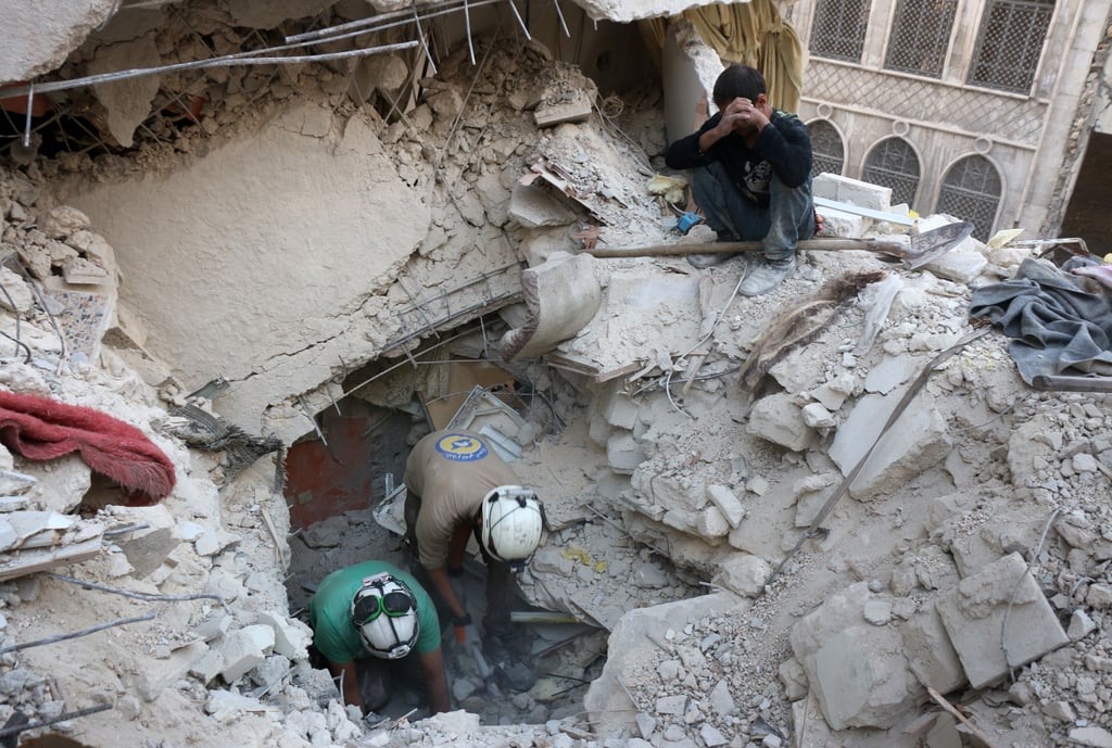 Syrian civil defense volunteers, the White Helmets, search for victims in Aleppo after an
