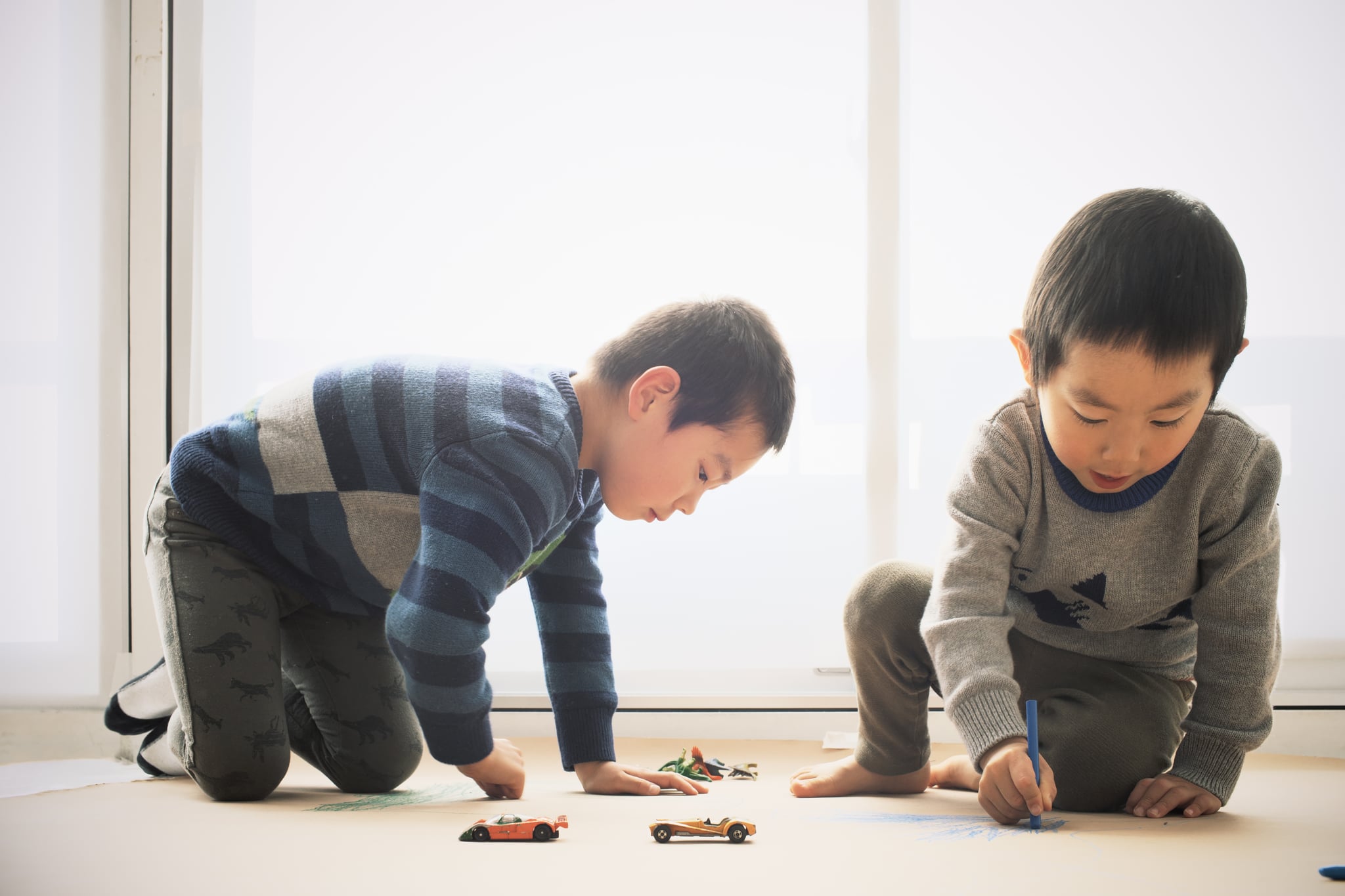 Young boy drawing with siblings at home