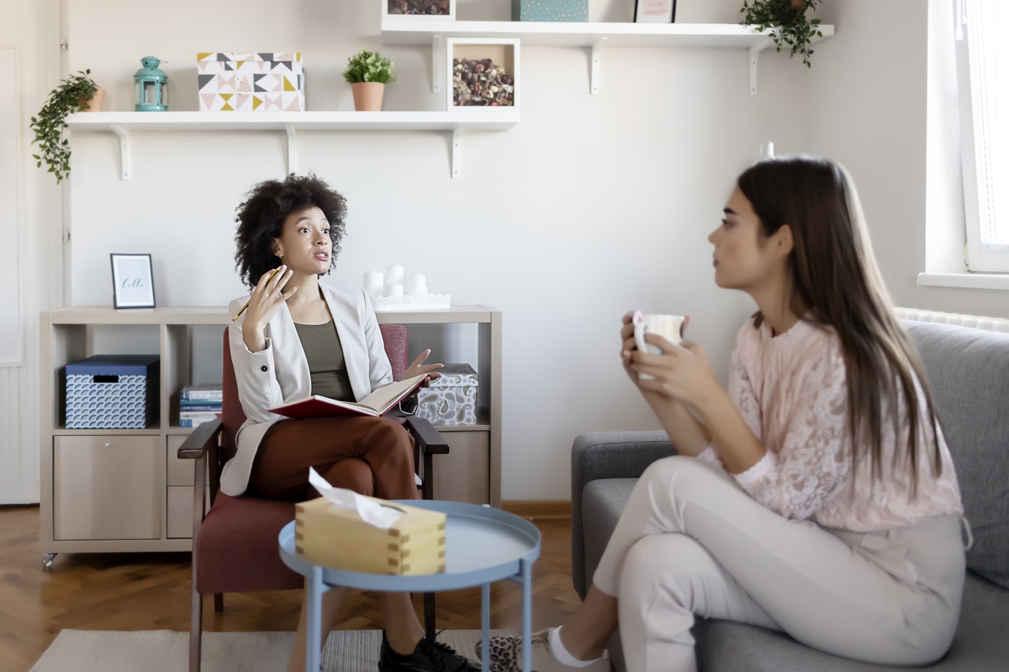 Young woman visiting therapist for in-person therapy vs. virtual therapy.