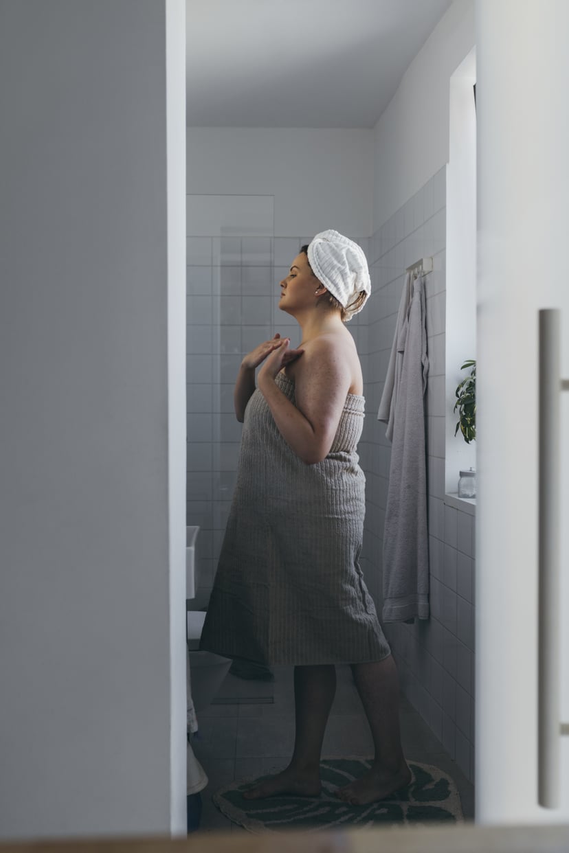 A beautiful plus size woman standing in front of the mirror in the bathroom after a shower