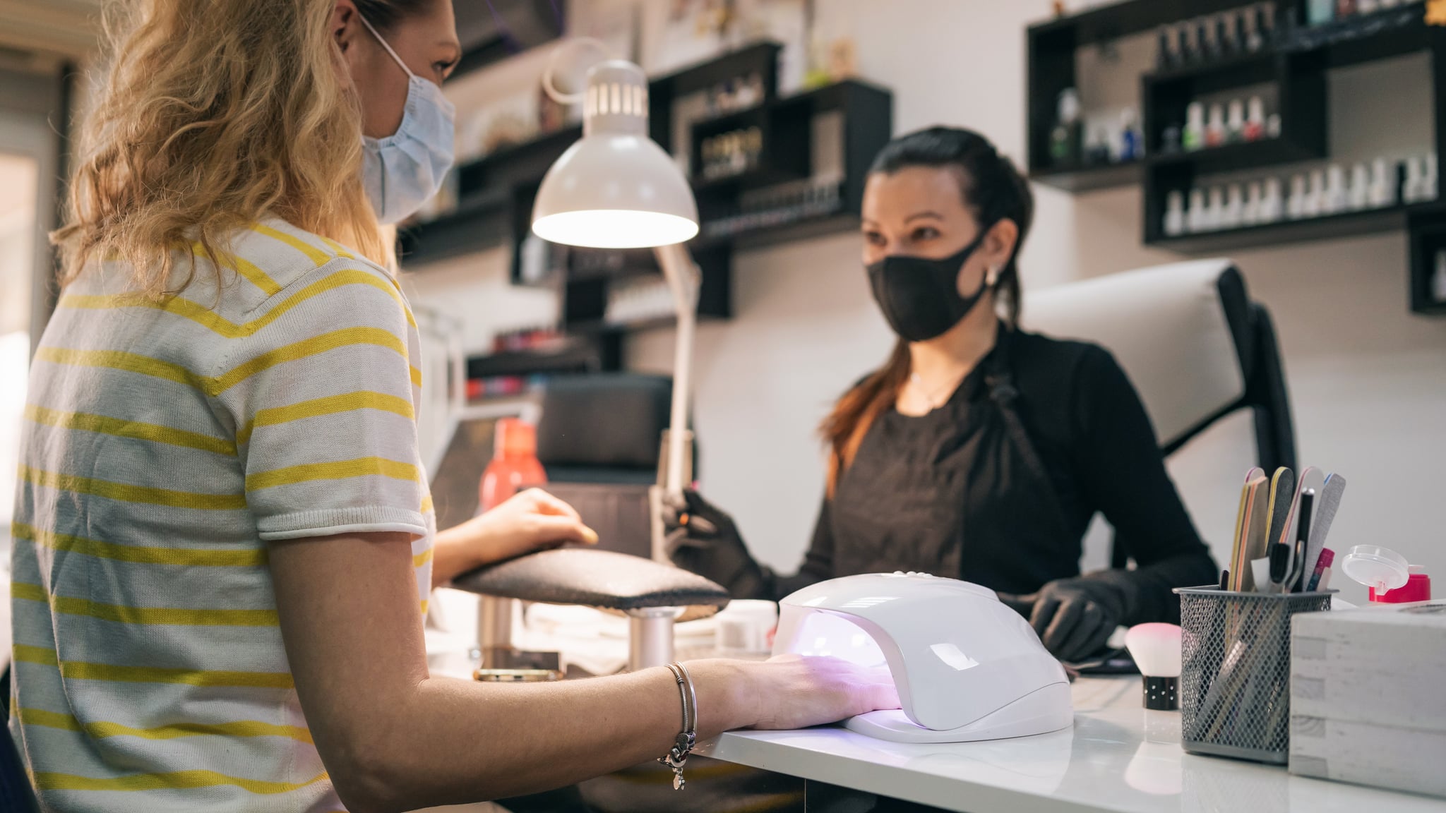 UV lamp gel polish manicure process. Salon procedure. The master coats the client's nails with a varnish.