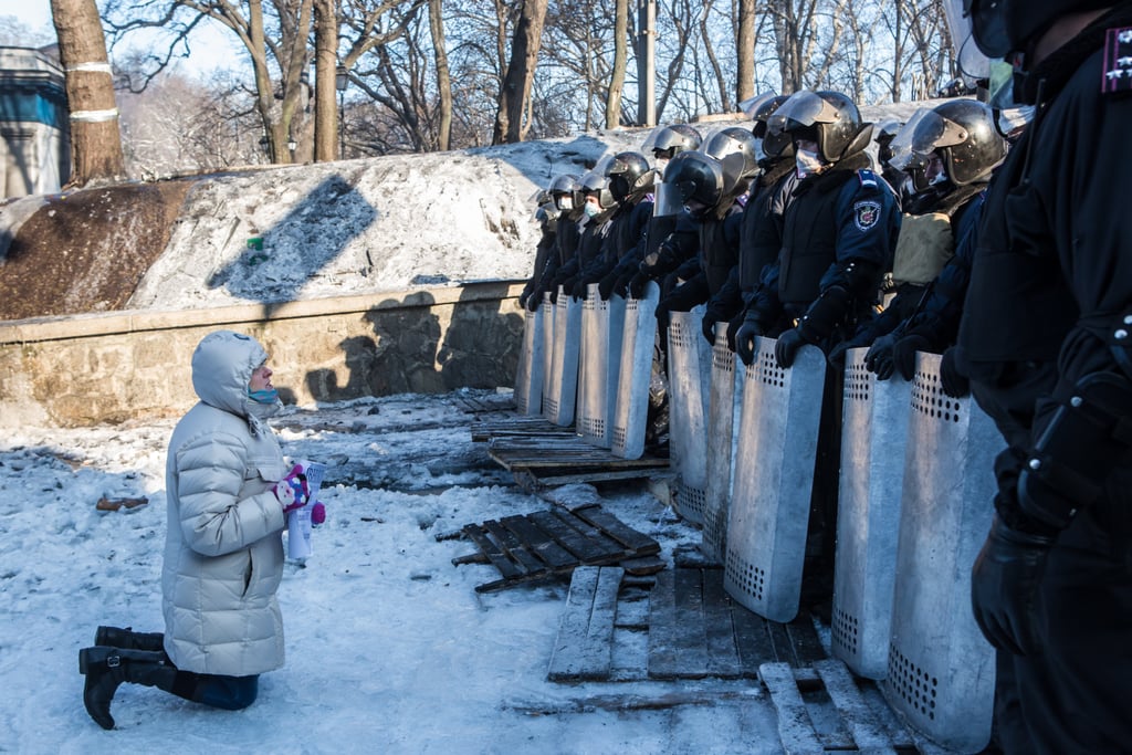 A woman spoke with police offers while kneeling in the snow.