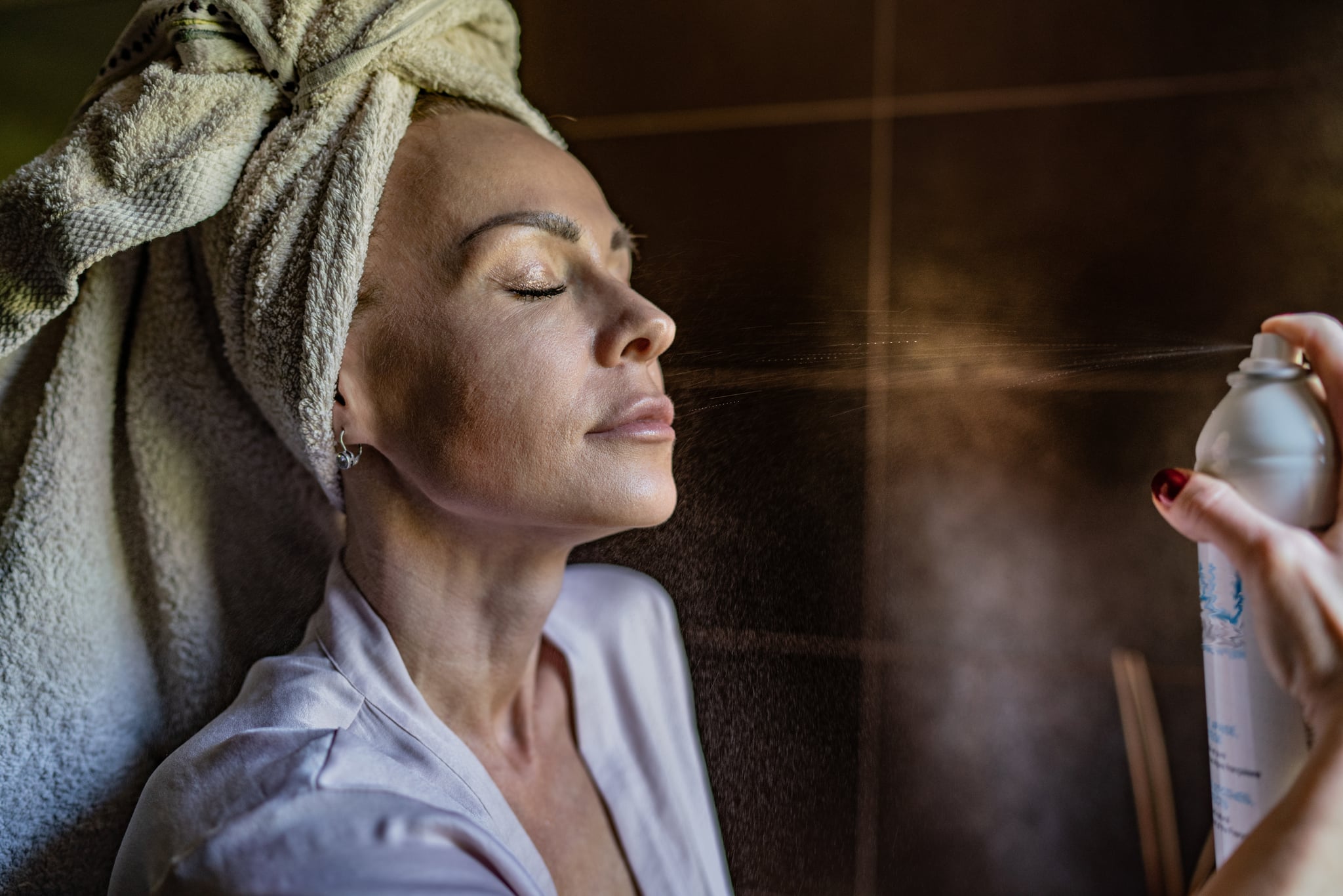 Beautiful adult woman using thermal spray for face