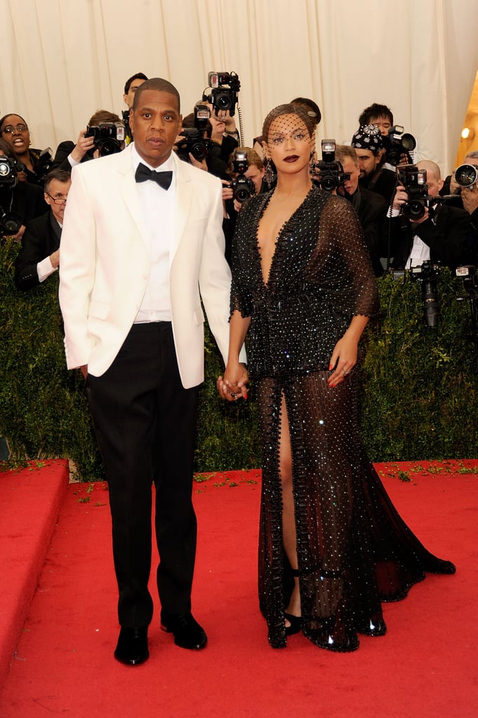 Making for what is perhaps one of our favorite Met Gala looks of all time, Beyoncé wore a black beaded Givenchy dress. The design was complete with a front slit, sheer details, and a plunging neckline — and Beyoncé accessorized with nothing but a birdcage veil and chunky earrings. Her look was romantic, slightly gothic, and dramatic for the Charles James exhibit. Meanwhile, JAY-Z kept it light up on top but accessorized with a black bow-tie to match Beyoncé's vibes.