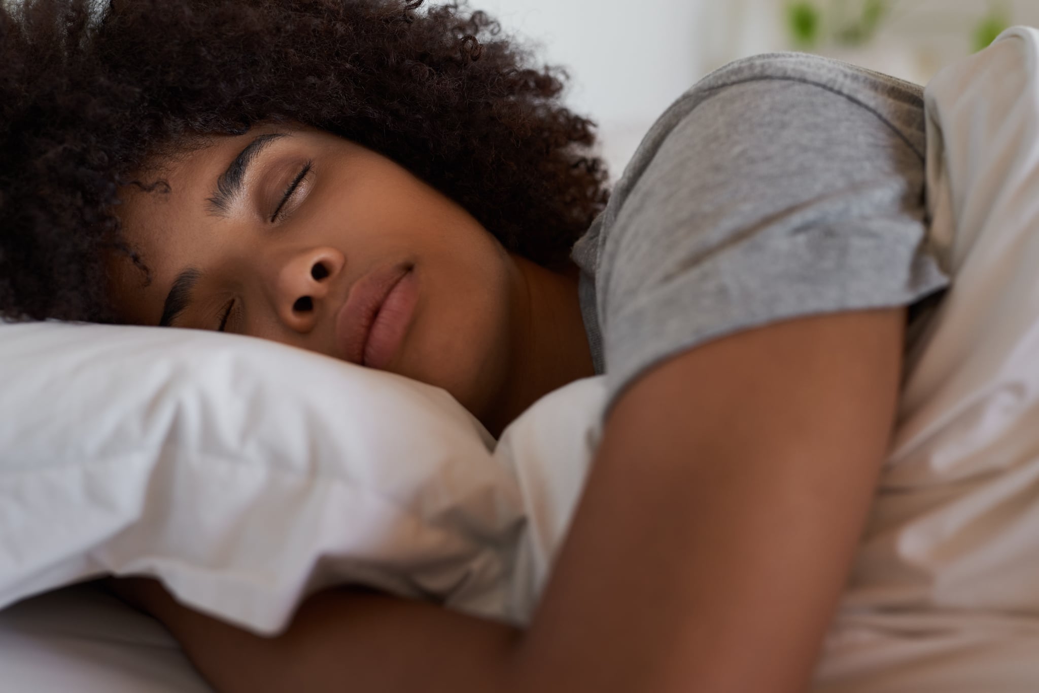 Close-up of a young African woman lying fast asleep in her comfortable bed at home in the morning