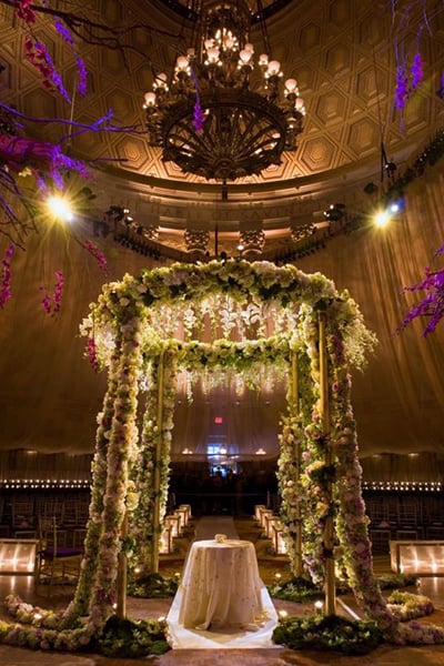 This chuppah overflowing with greenery lends a mystical vibe to an urban venue.