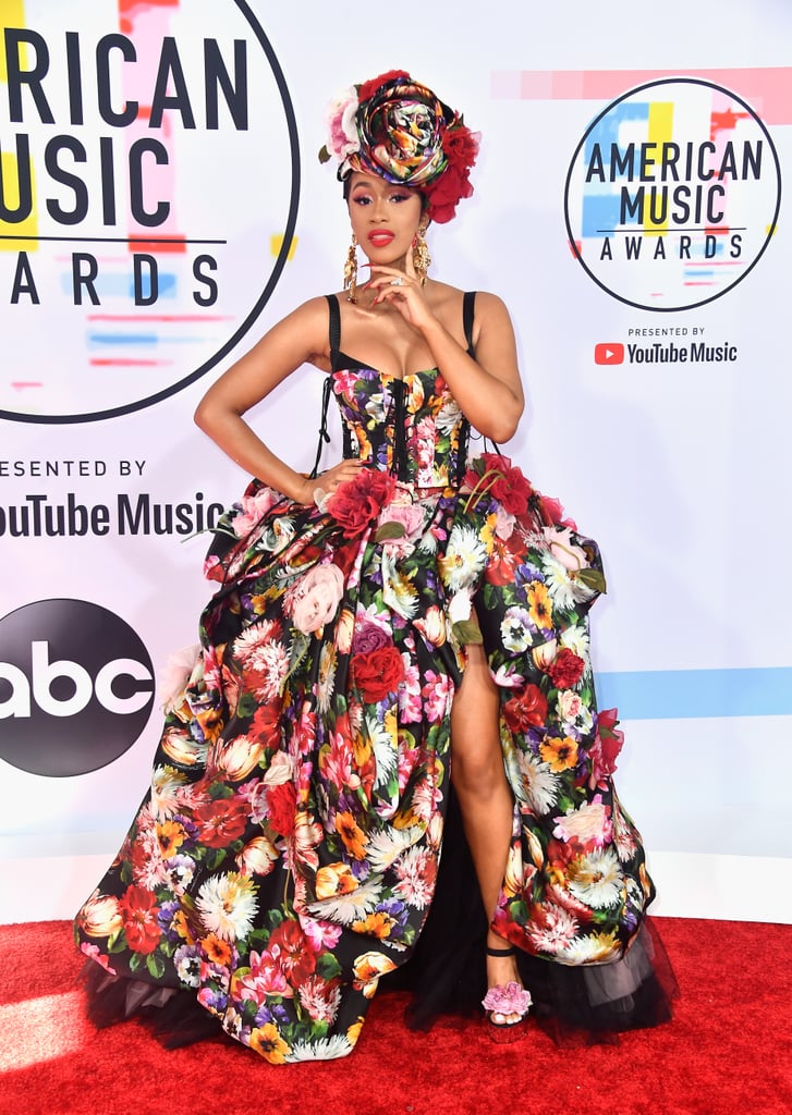 Cardi stepped out on the American Music Awards red carpet wearing a Dolce & Gabbana floral gown with a matching headpiece, gold earrings, and floral heels.