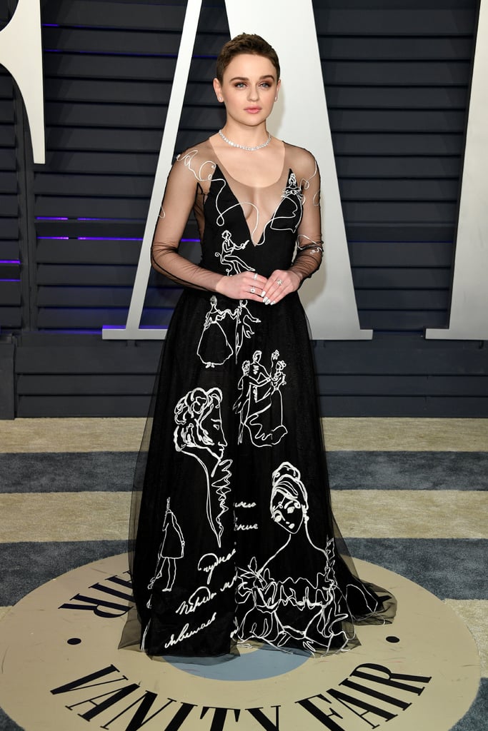 At the 2019 Vanity Fair Oscar Party wearing a black v-neck gown with sheer sleeves by Yanina Couture, jewelry by Swarovski, and heels by Christian Louboutin.
