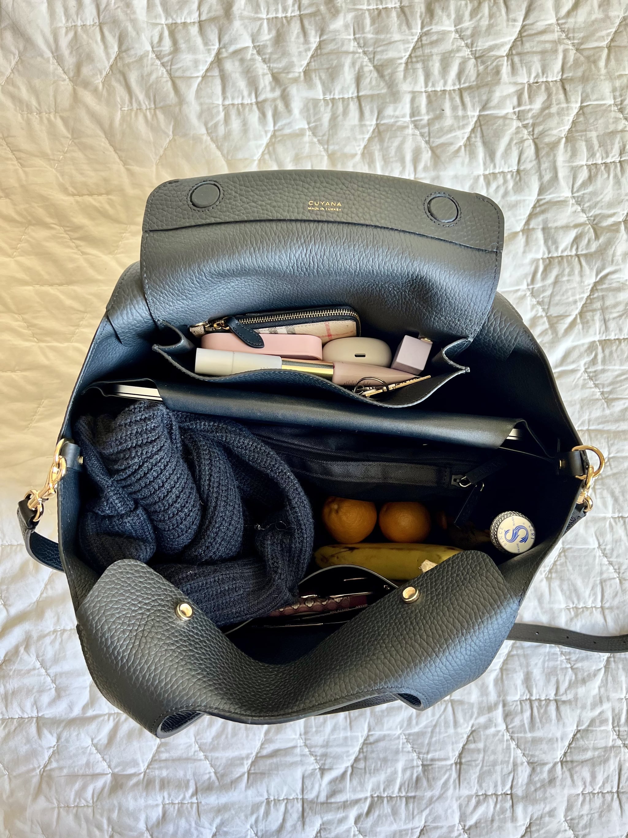 The Cuyana System Tote packed with items like a laptop, tech case, a cardigan, fruits, and more.
