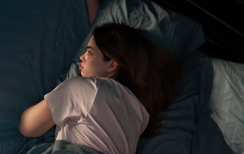 Woman lying in bed at night, trying the house tour sleep hack to fall asleep.