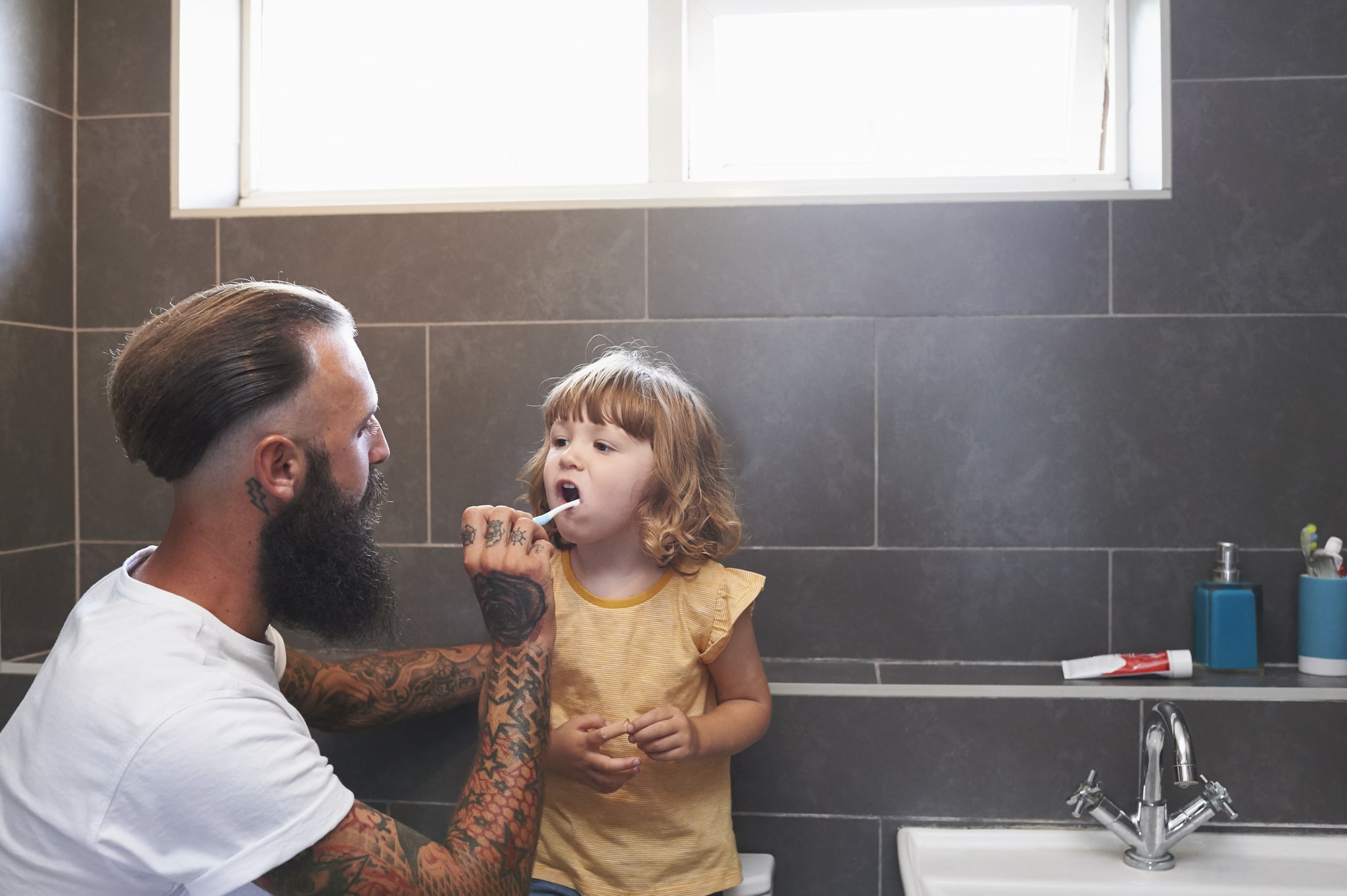 Daughter stands on WC so that Dad can brush her teeth