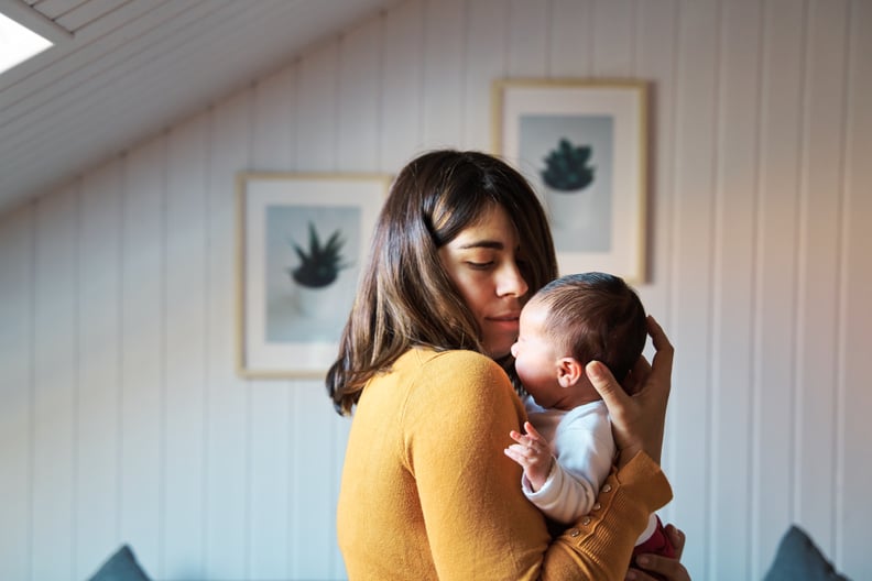 Side view of new mother comforting her newborn while crying. Baby getting used to noises and lights in her first days of life outside the womb.