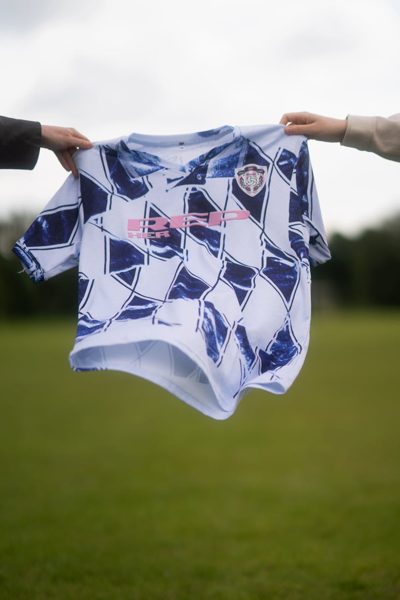 Two hands holding the a blue and white football shirts
