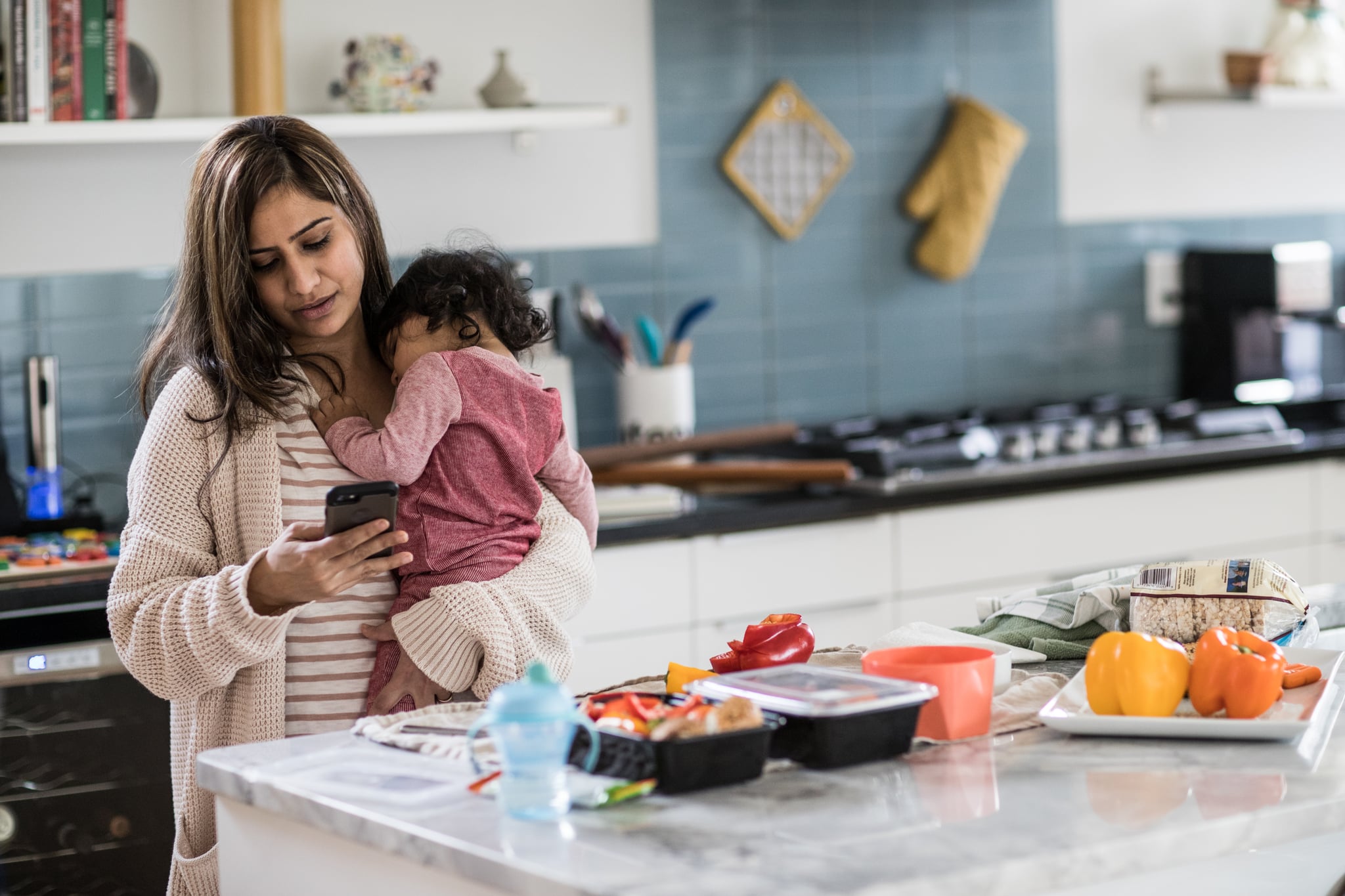 Mother holding baby and multi-tasking in kitchen