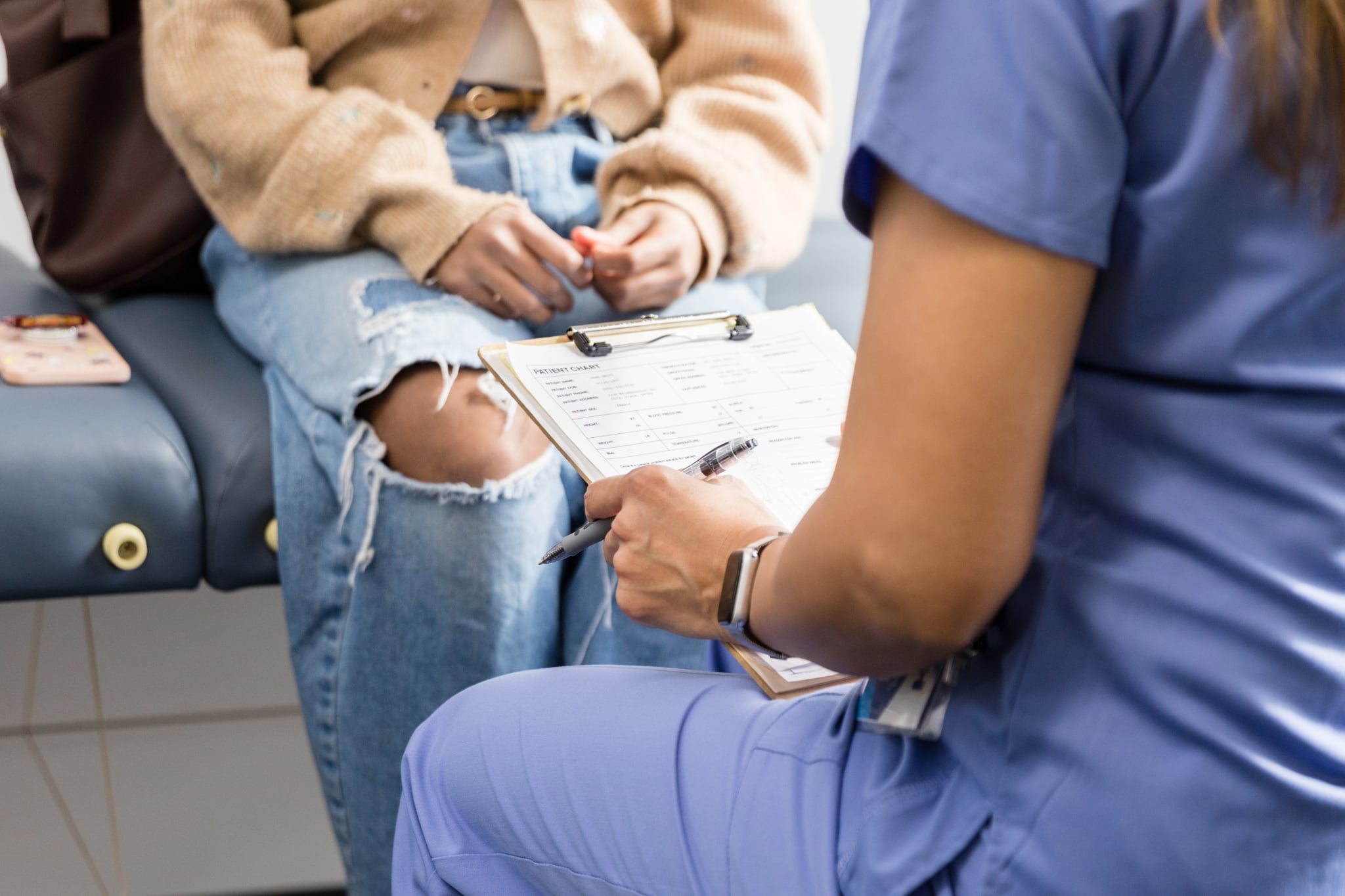 Woman talking through medical history with a doctor in an exam room.