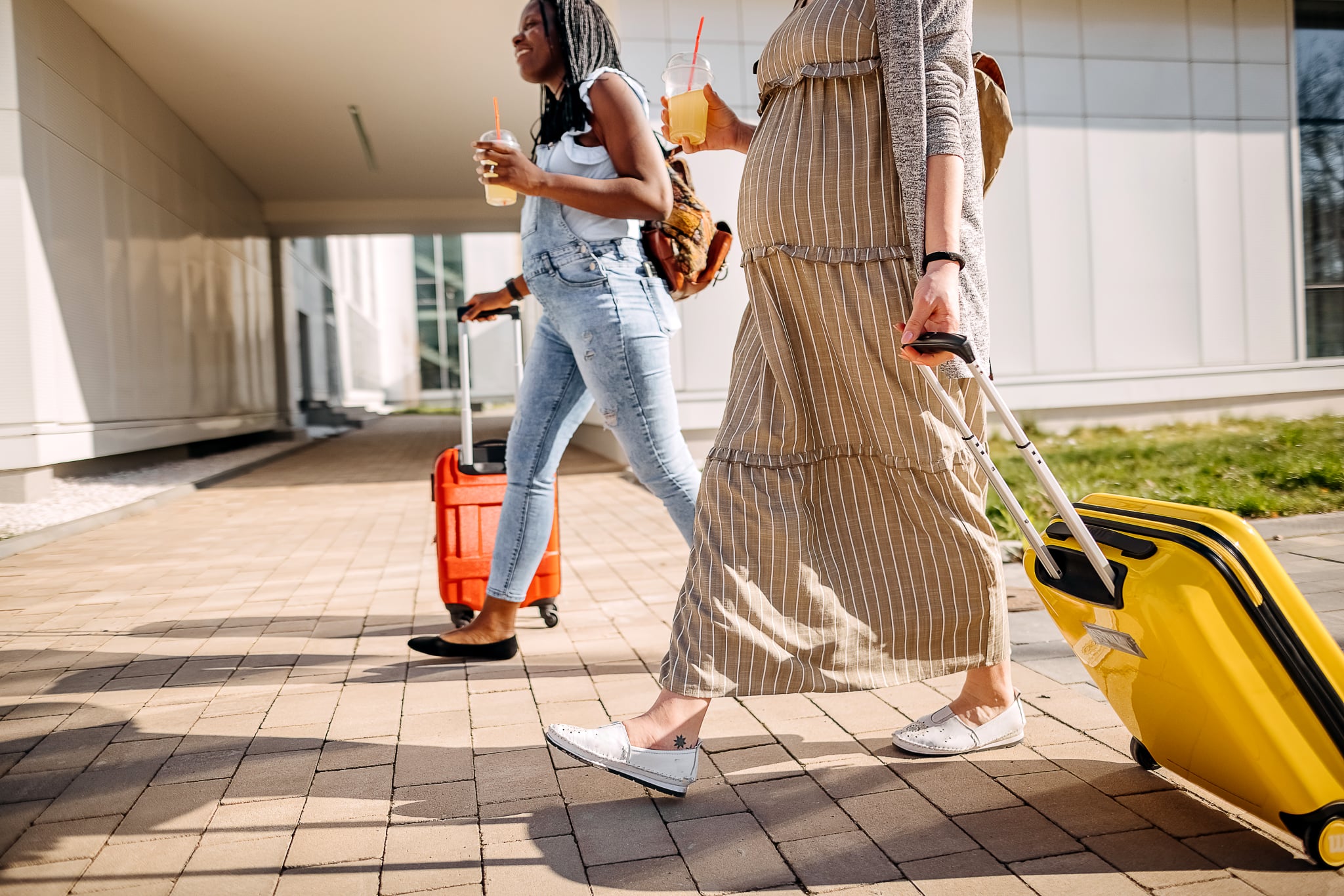 Two young pregnant women are walking around the city and pulling suitcases