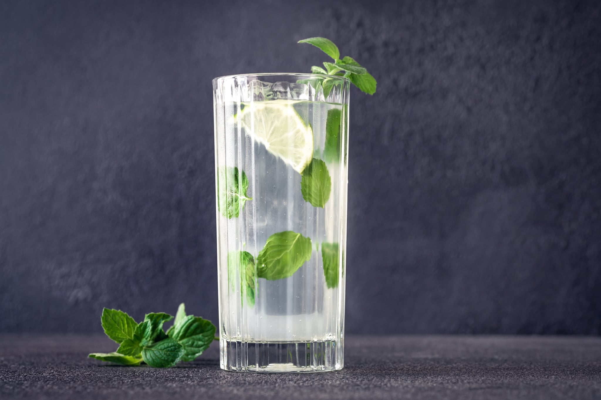 Glass of mojito cocktail on dark background