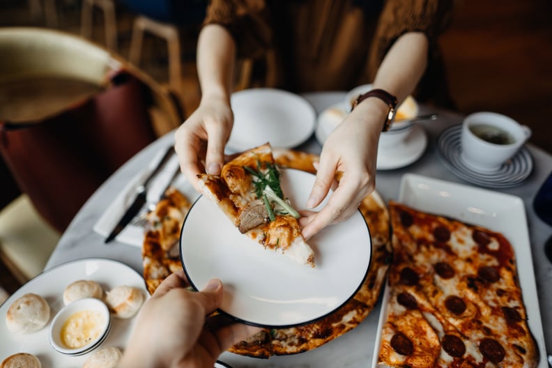 Close up of couple enjoying meal and sharing pizza in a restaurant