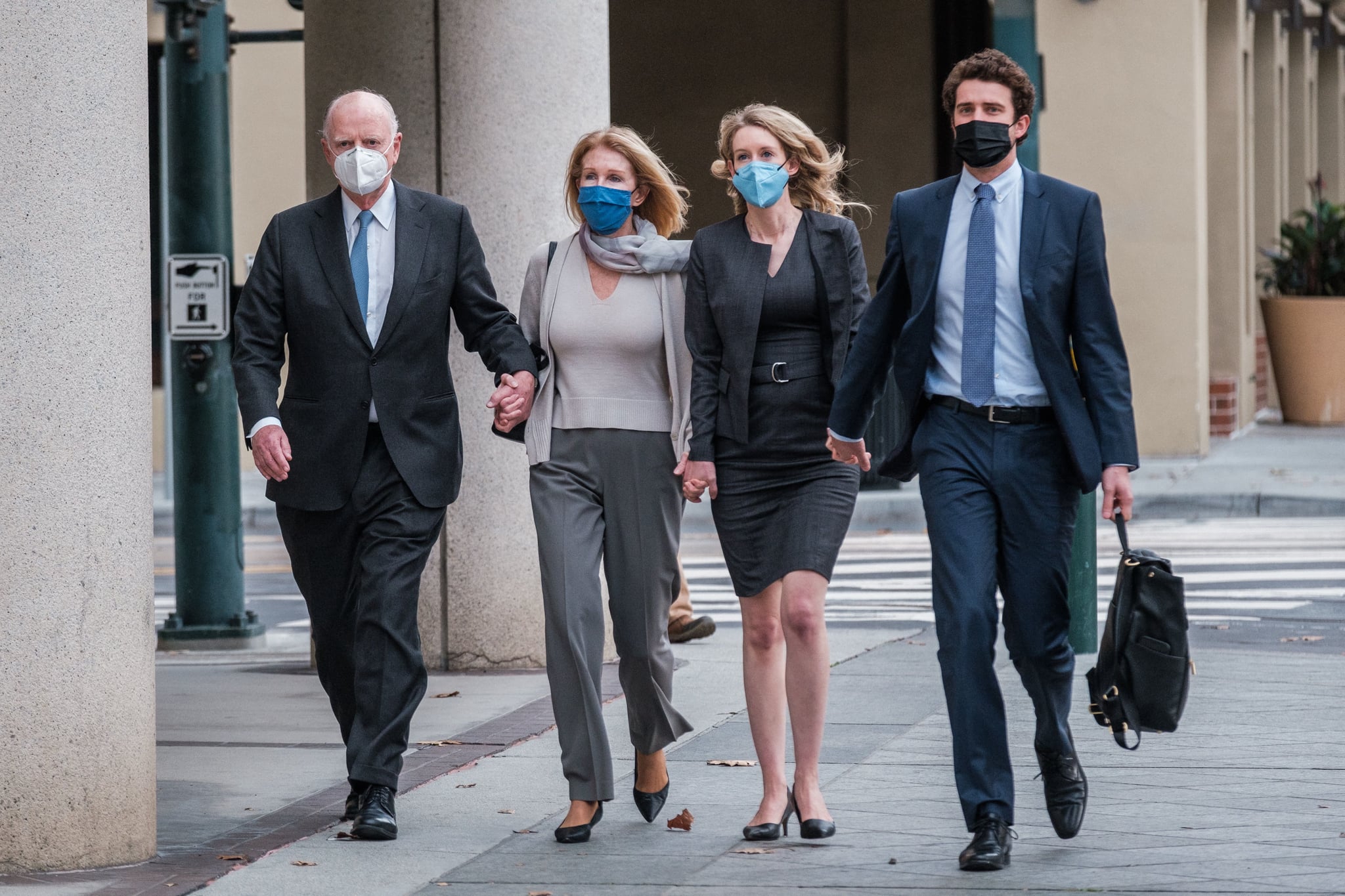 Elizabeth Holmes (2R) walks with her partner Billy Evans (R) and her parents Christian (L) and Noel (2L) Holmes, to the federal court to hear the verdict in her fraud trial in San Jose, California, January 3, 2022. - Fallen US biotech star Elizabeth Holmes was convicted on Monday of defrauding investors in her blood-testing startup Theranos, in a high-profile case seen as an indictment of Silicon Valley culture.Jurors took seven days of deliberations to reach their verdict, finding her guilty of four counts of tricking investors into pouring money into what she claimed was a revolutionary testing system. (Photo by Nick Otto / AFP) (Photo by NICK OTTO/AFP via Getty Images)
